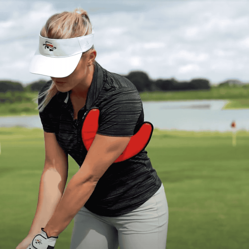 Woman playing golf on a green course with a lake in the background with a boomerrang